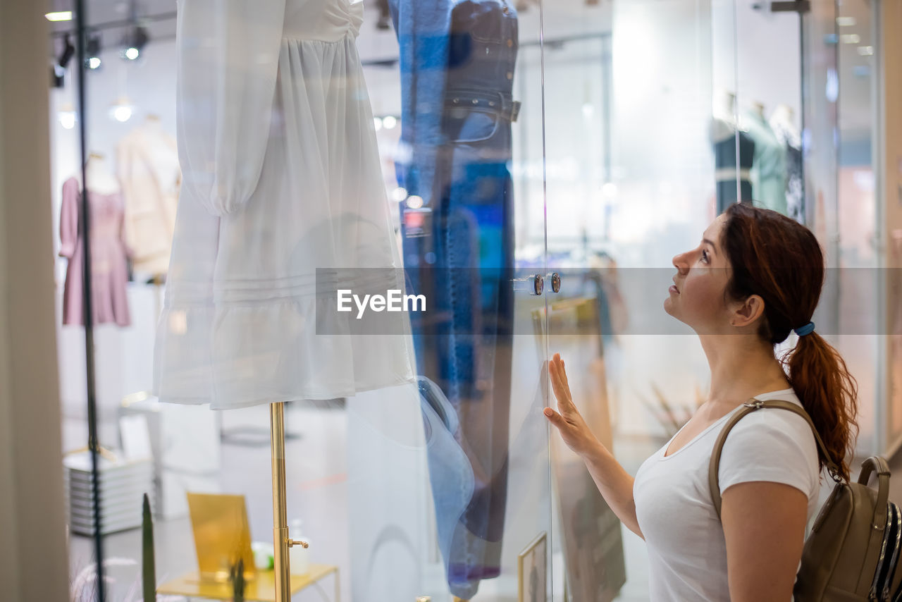 Woman looking through window at store