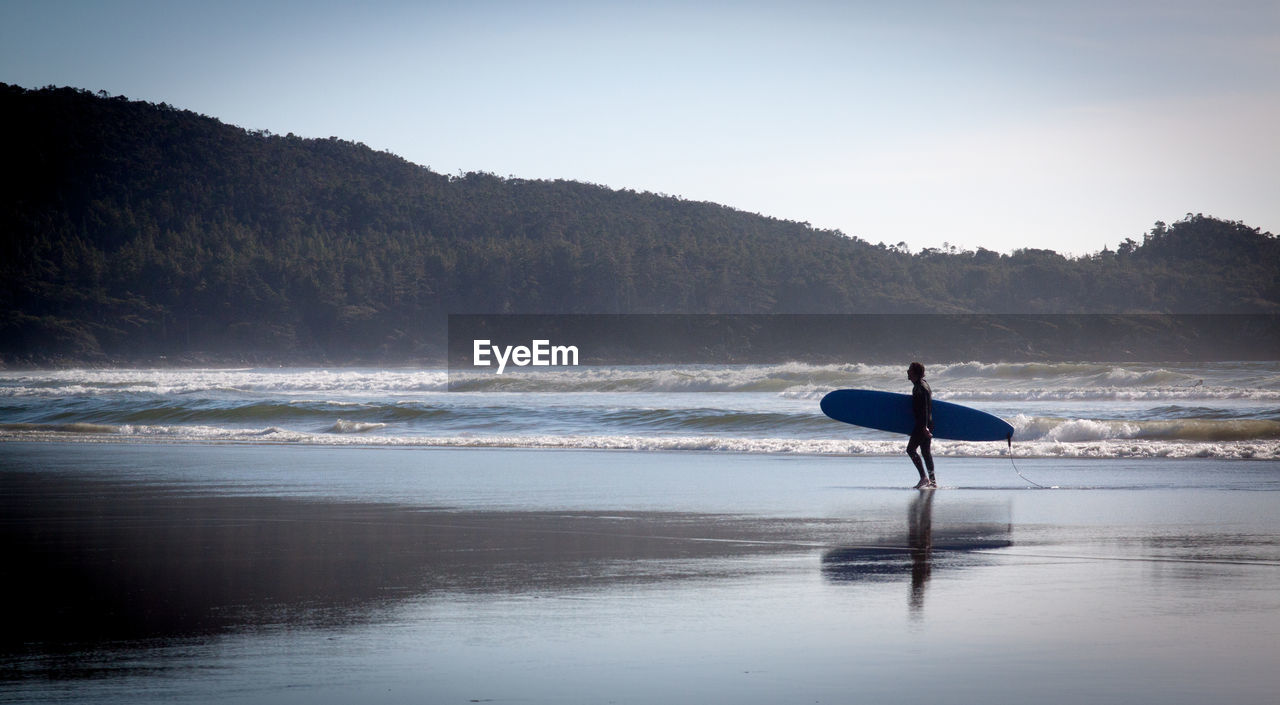 Male surfer walking in calm sea