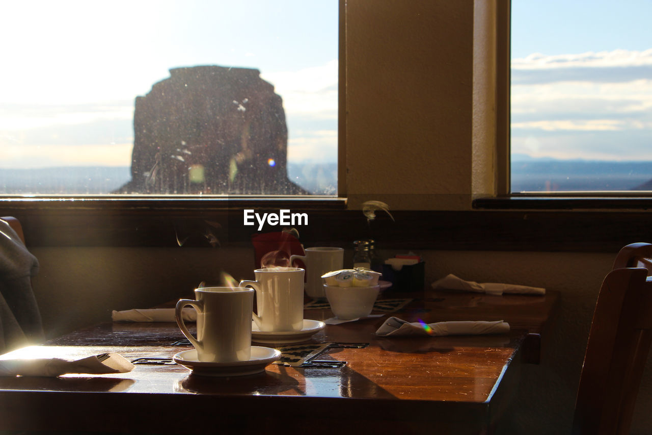 GLASS OF TABLE AGAINST SKY SEEN FROM WINDOW