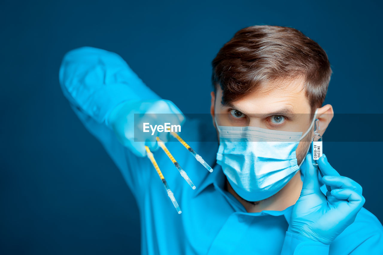 Portrait of senior man wearing mask against blue background