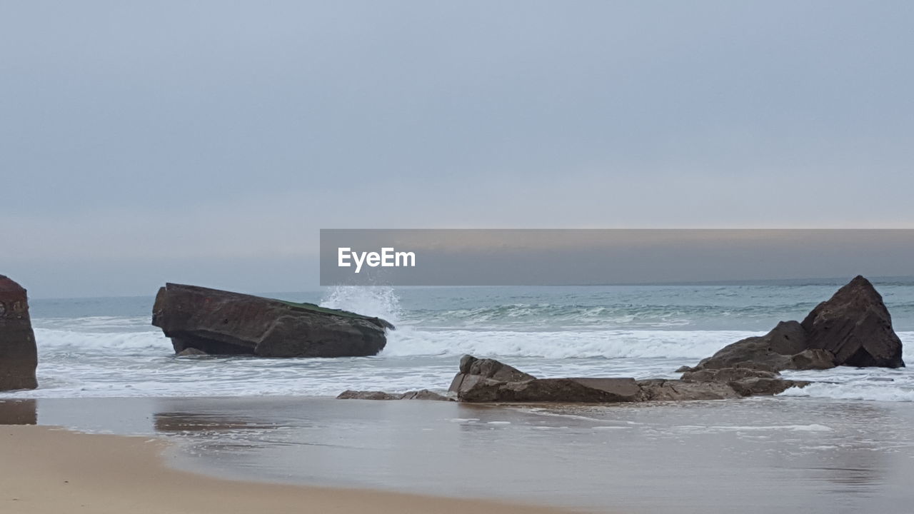 ABANDONED BOAT ON SHORE AGAINST SKY