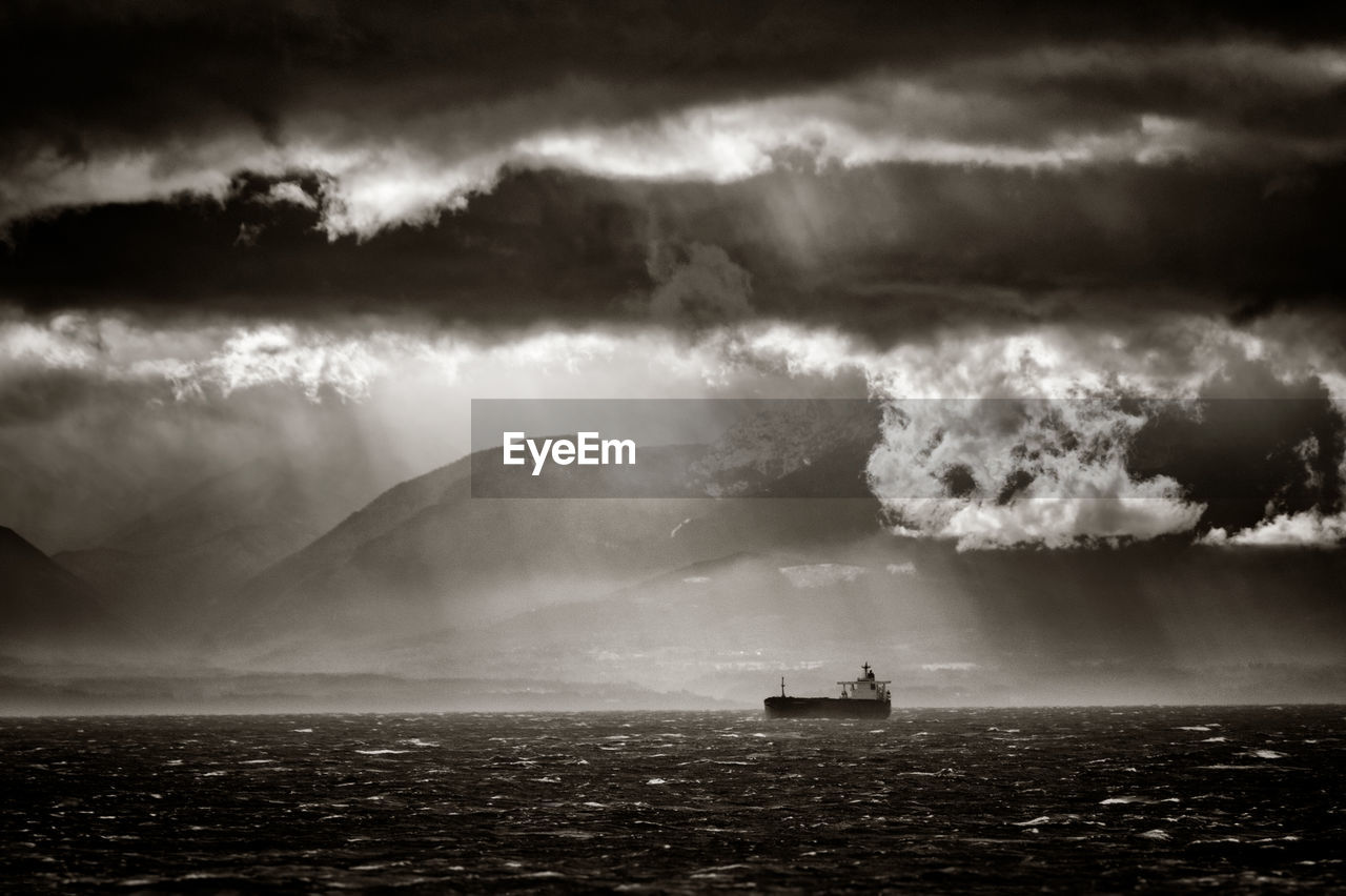 Ship in sea against cloudy sky