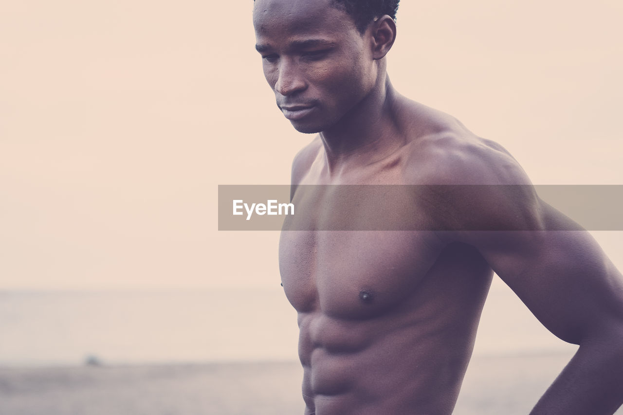 Shirtless muscular man standing at beach