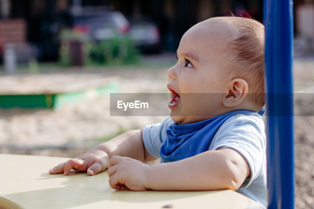 Cute happy smiling baby boy walking at children playground outdoors