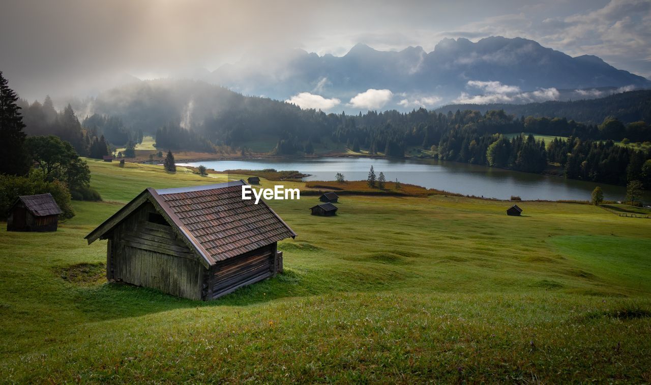 Scenic view of house by lake on mountains against sky