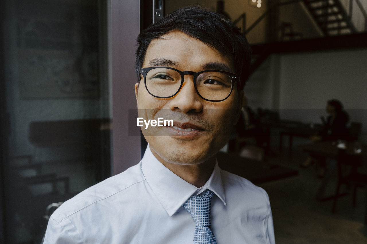 Happy male entrepreneur looking away in office