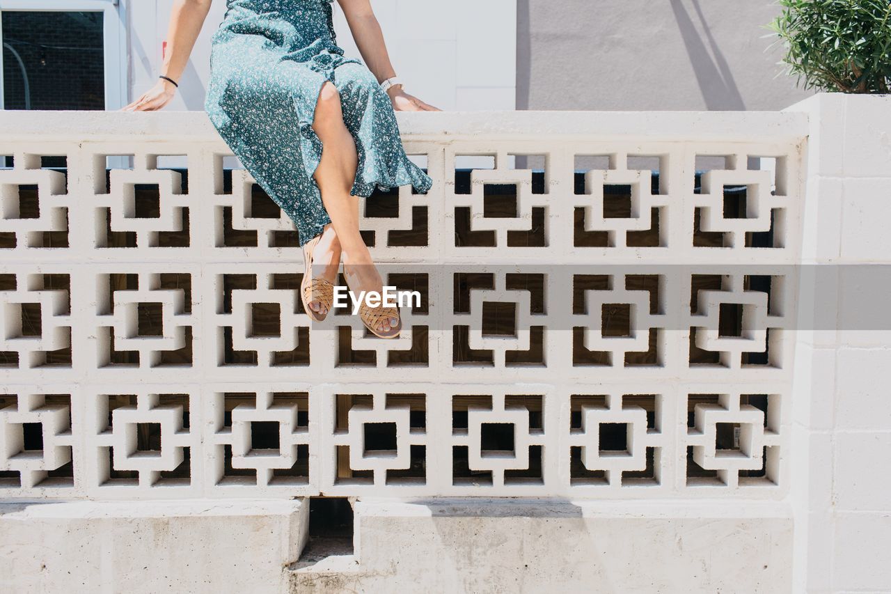 Low section of woman sitting on retaining wall