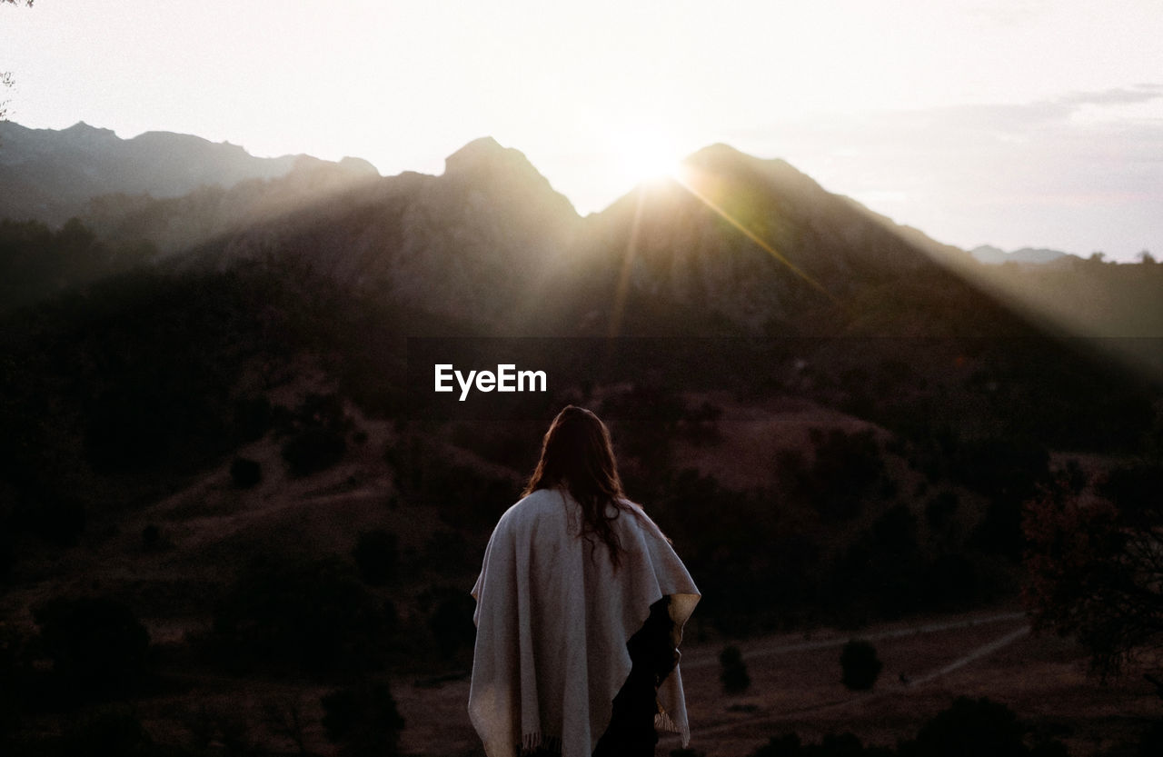 Rear view of woman looking at mountains against sky