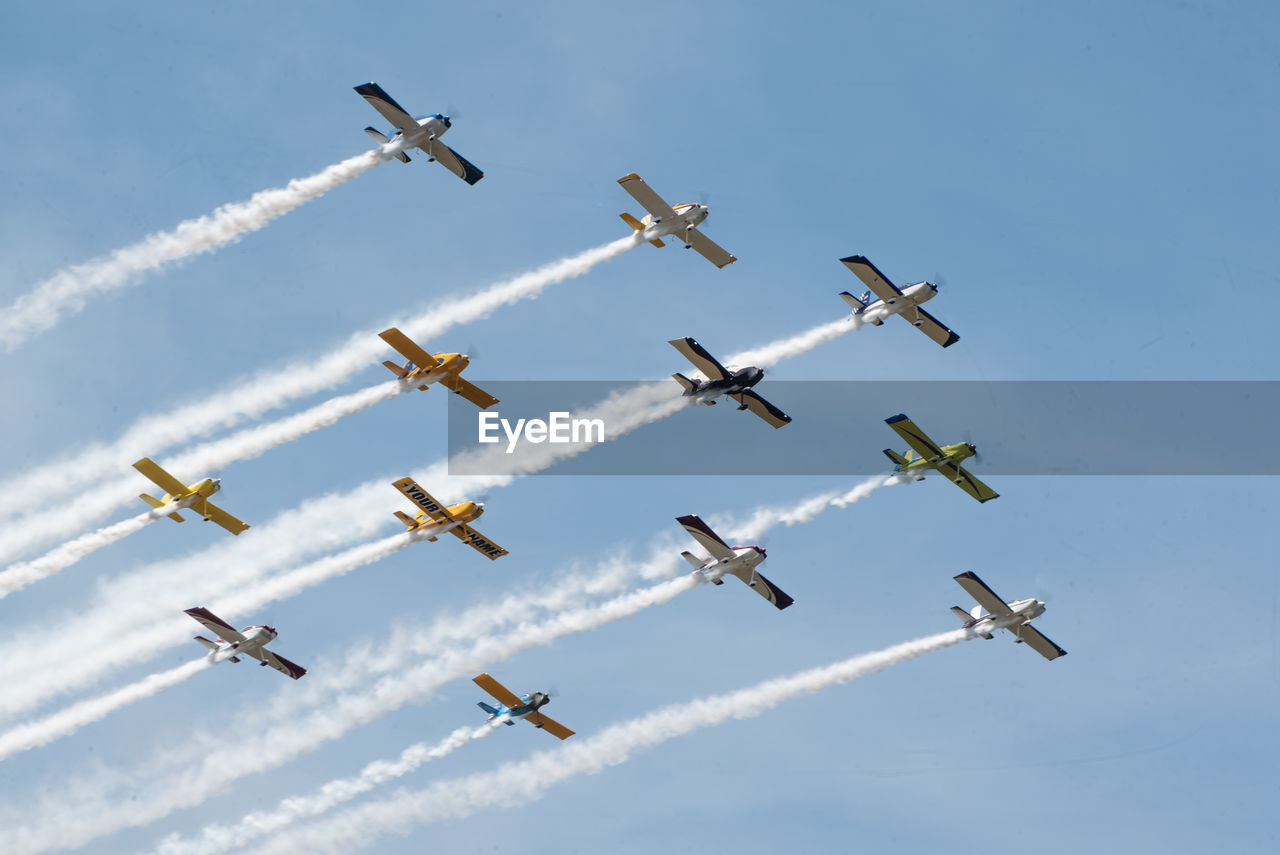 LOW ANGLE VIEW OF BIRDS FLYING AGAINST VAPOR TRAIL