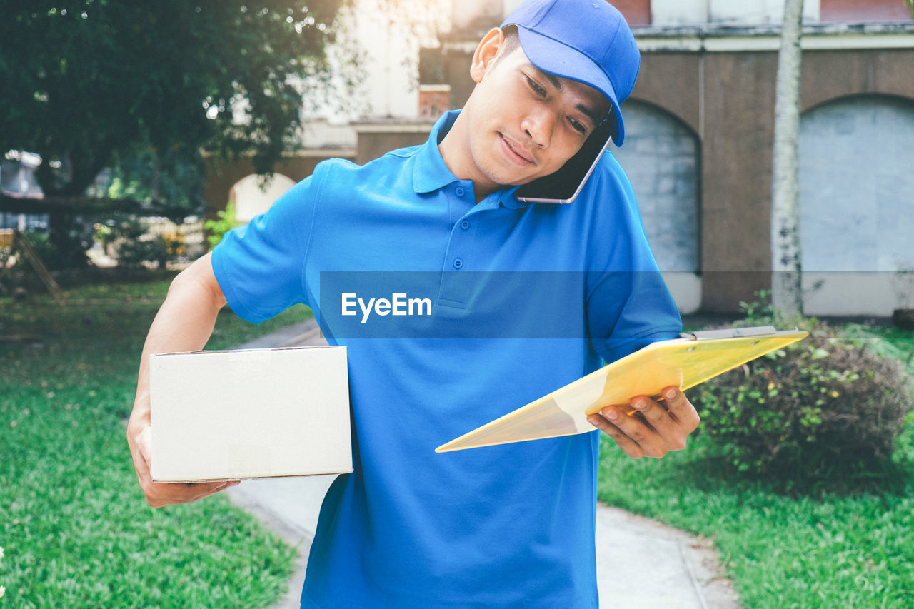 Delivery man with package talking on mobile phone