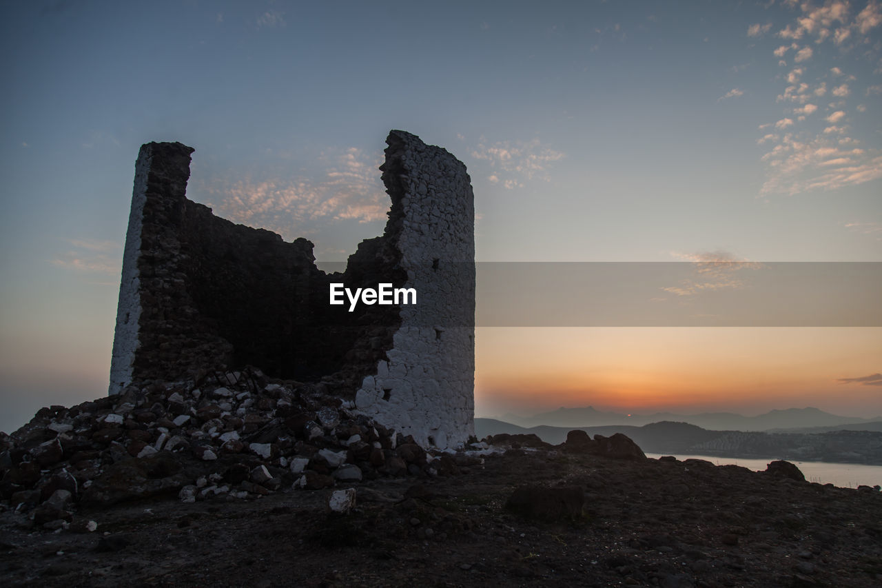 Rock formations of windmill against sky during sunset