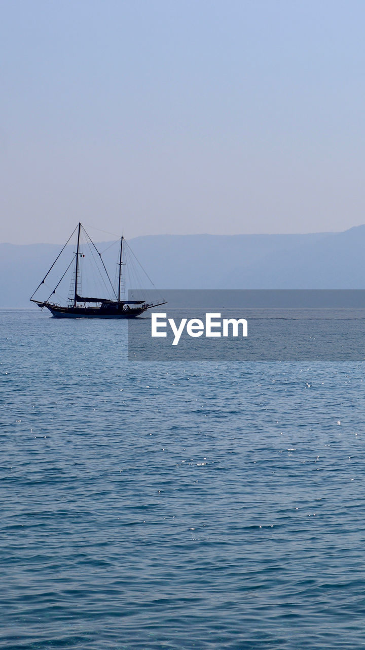 Sailboat sailing on sea against clear sky