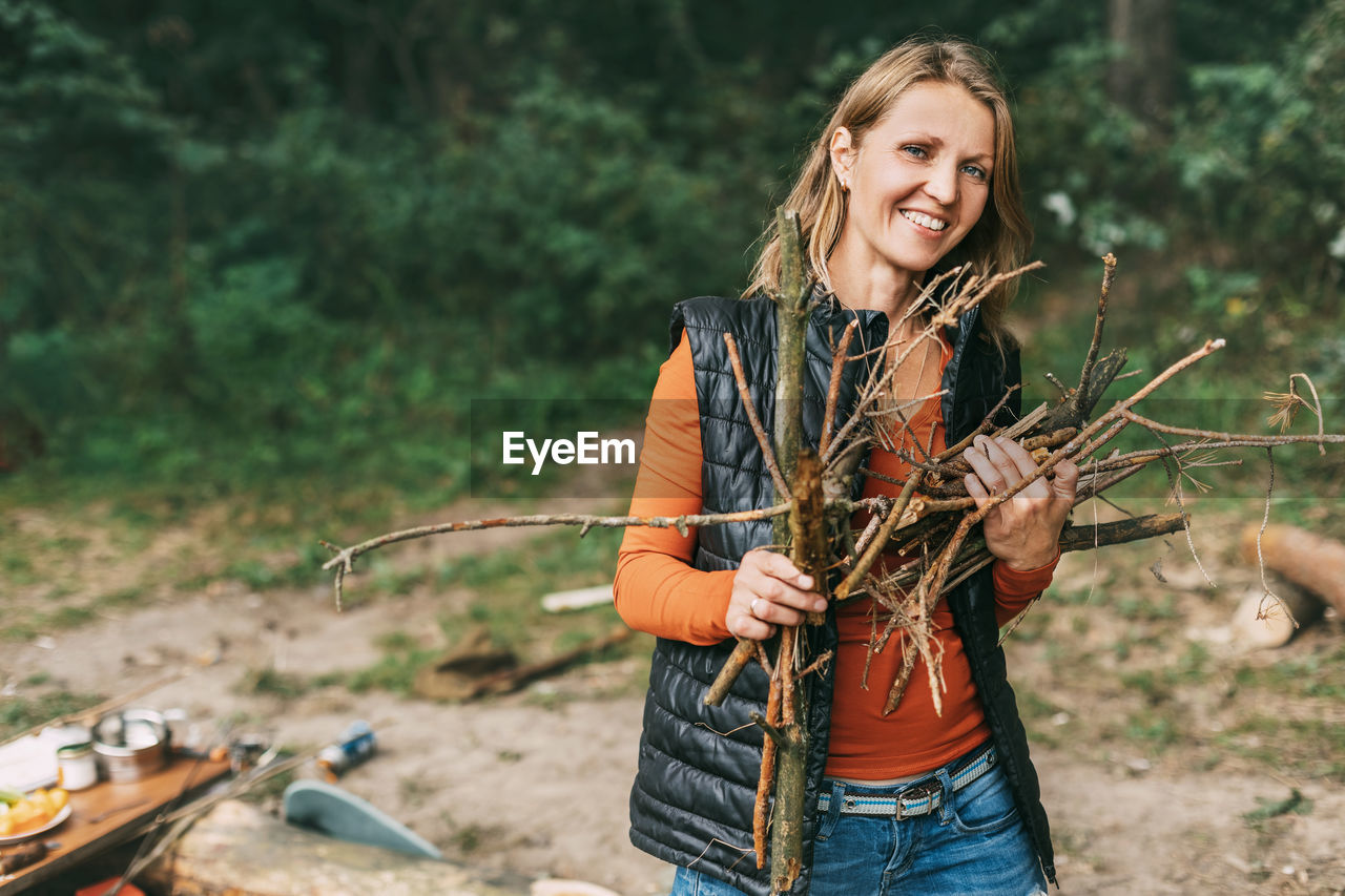 A tourist girl in nature collects firewood for a fire. a woman in close-up. 