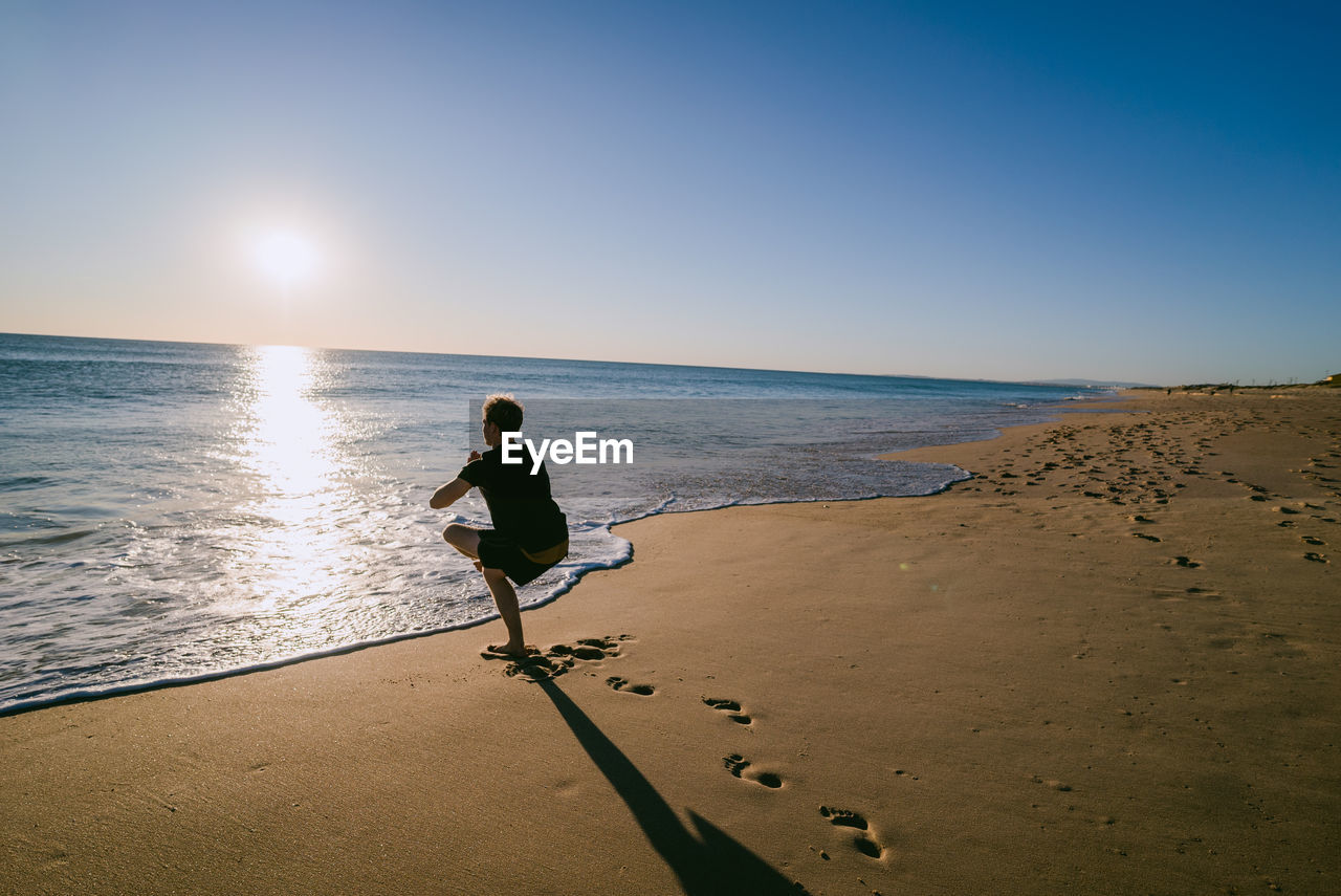 Full length of man exercising at beach