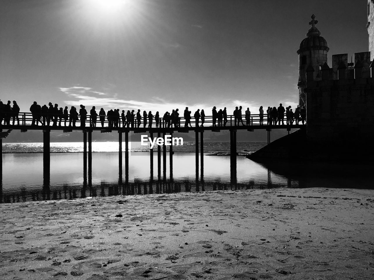 Silhouette people standing on bridge in front of church at beach