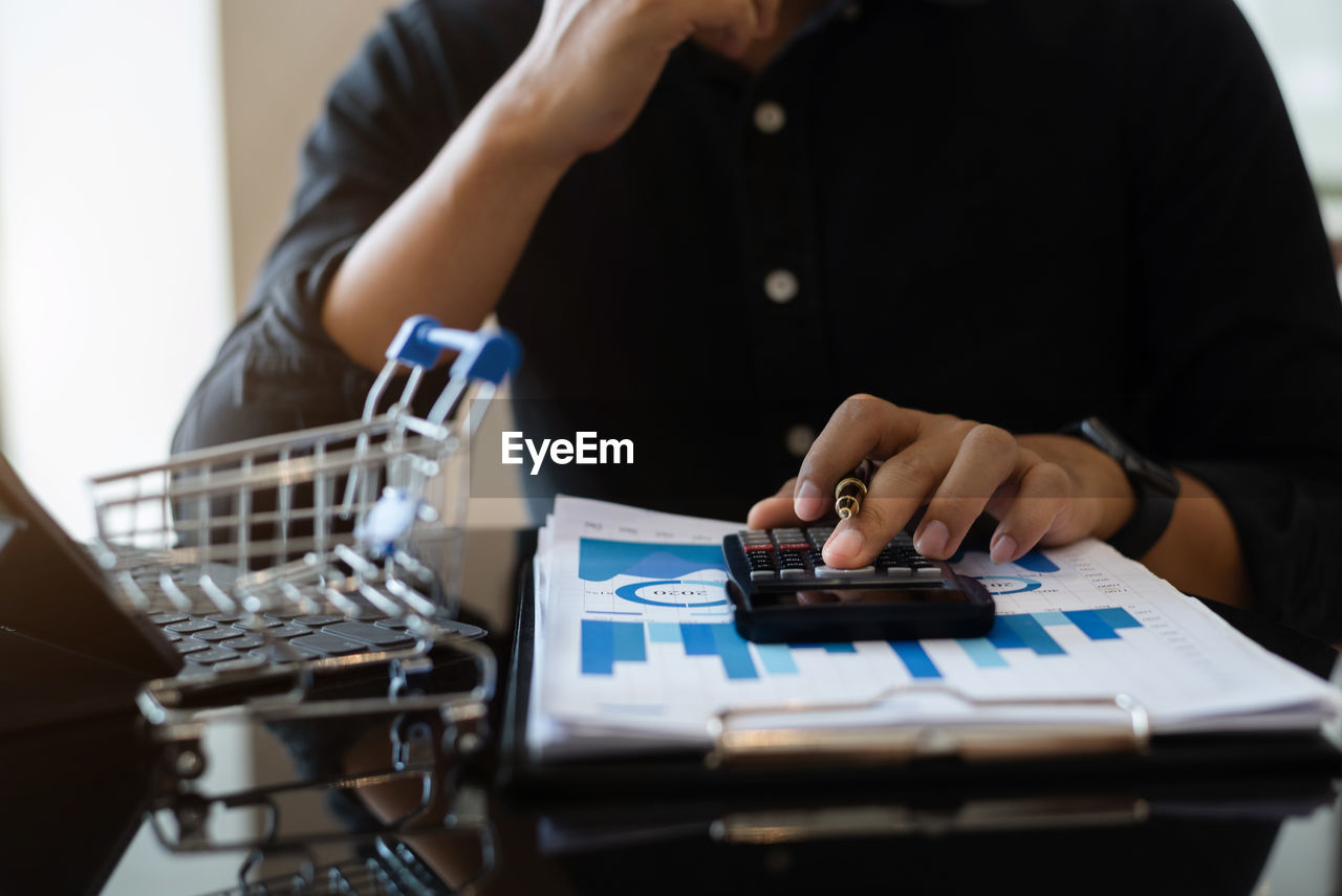 midsection of woman using calculator