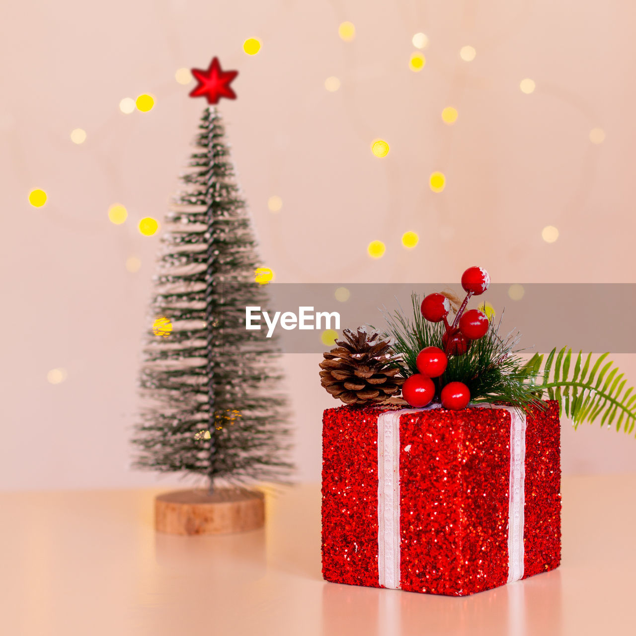 Red christmas gift box, christmas tree with red star on the background of bokeh christmas lights