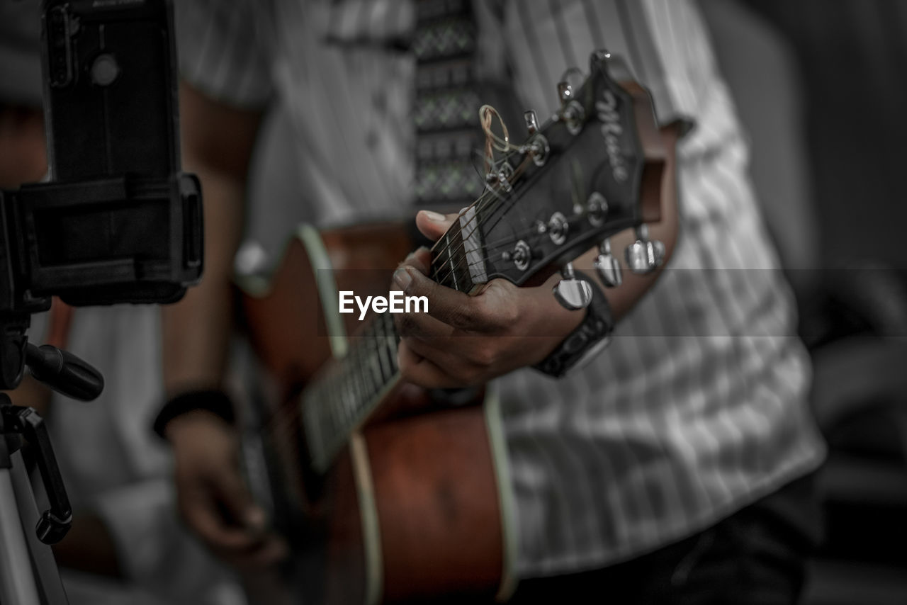 midsection of man playing guitar outdoors