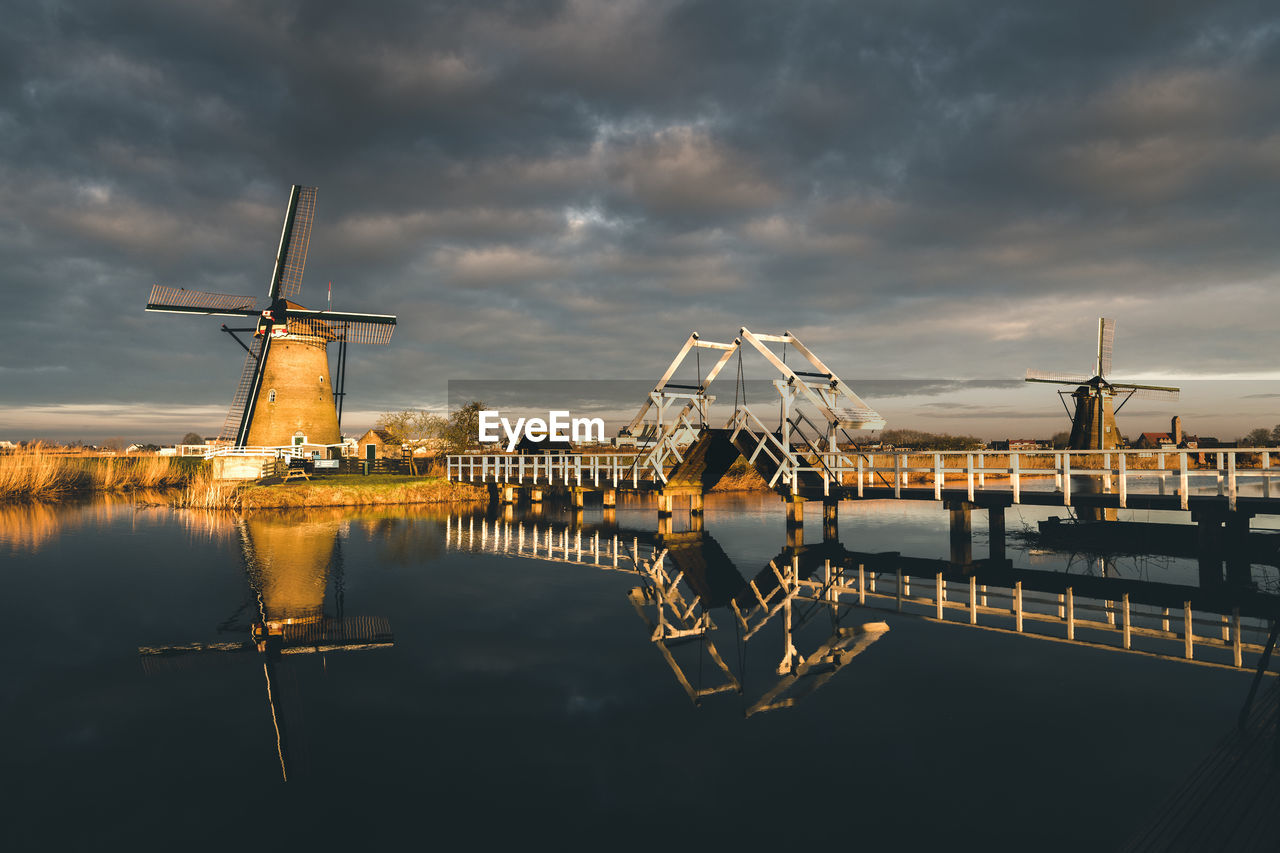 Windmill against sky by lake