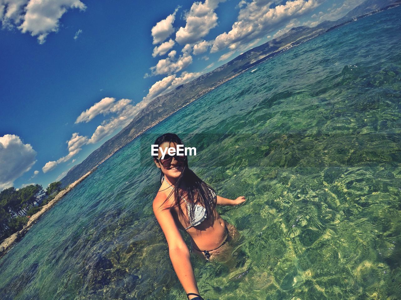 Portrait of young woman wearing bikini standing in sea