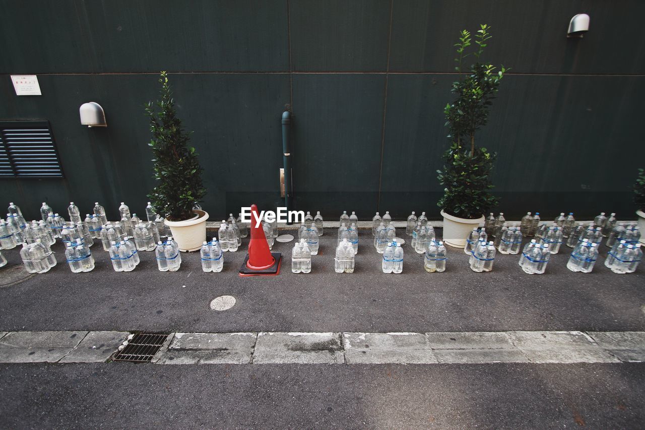 High angle view of water bottles on sidewalk by wall