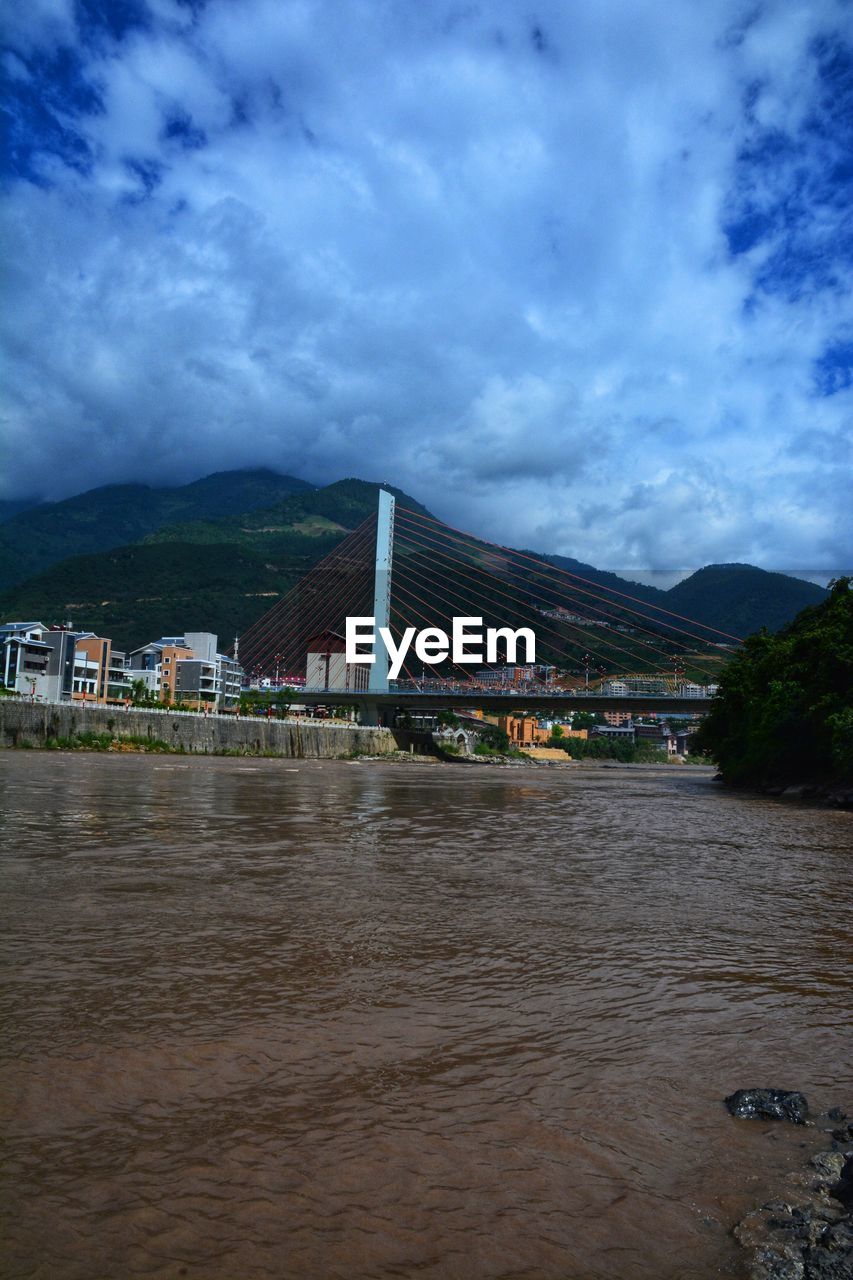 RIVER BY BUILDINGS IN TOWN AGAINST SKY