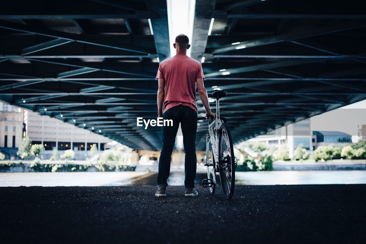 Rear view of man standing under bridge