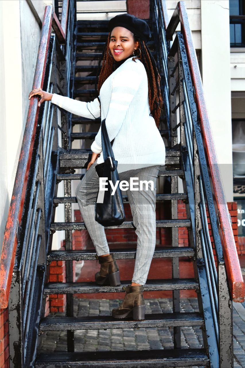 Portrait of smiling woman walking on staircase