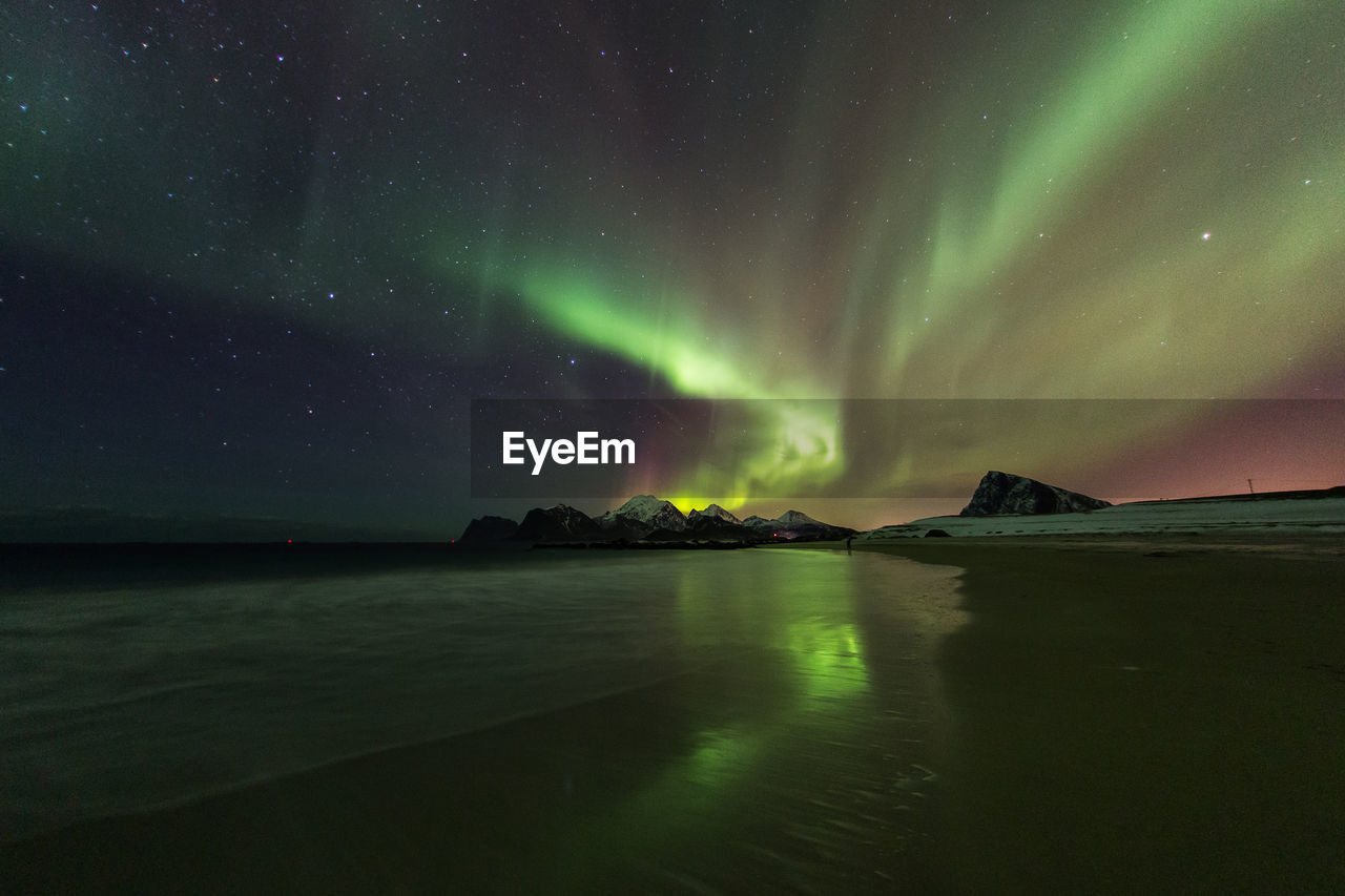 Scenic view of beach against aurora borealis at night