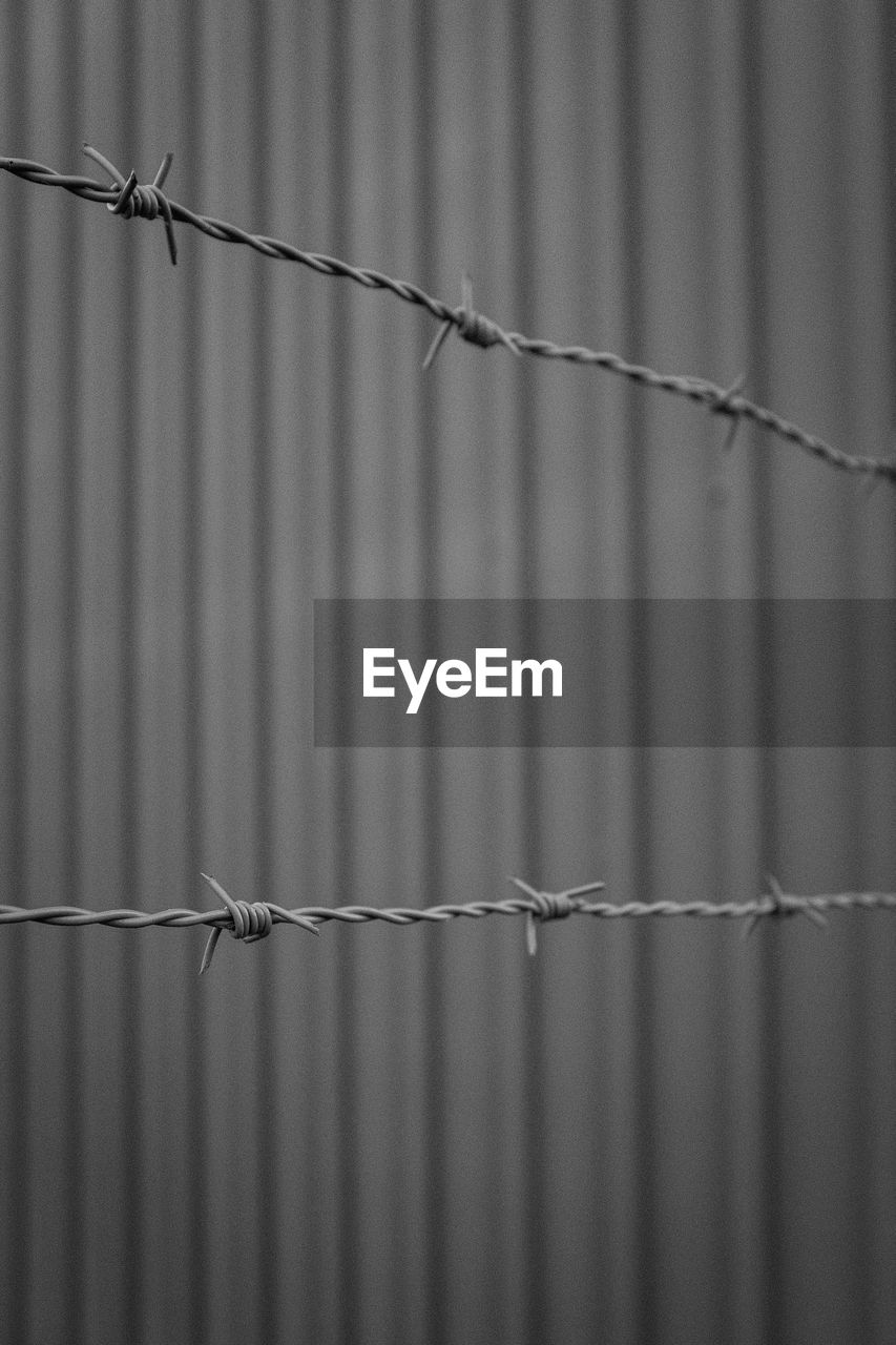 Close-up of barbed wire against wall