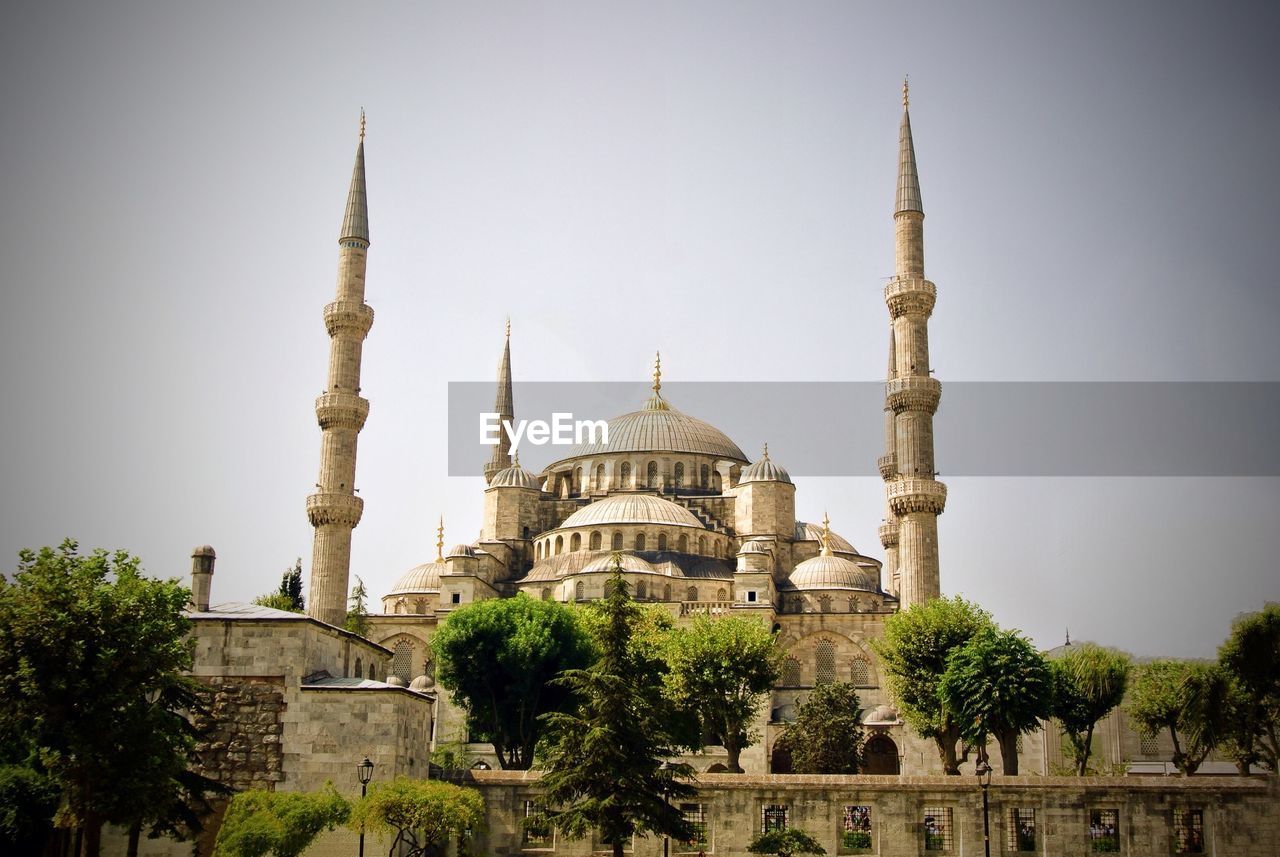 Low angle view of blue mosque and trees against clear sky