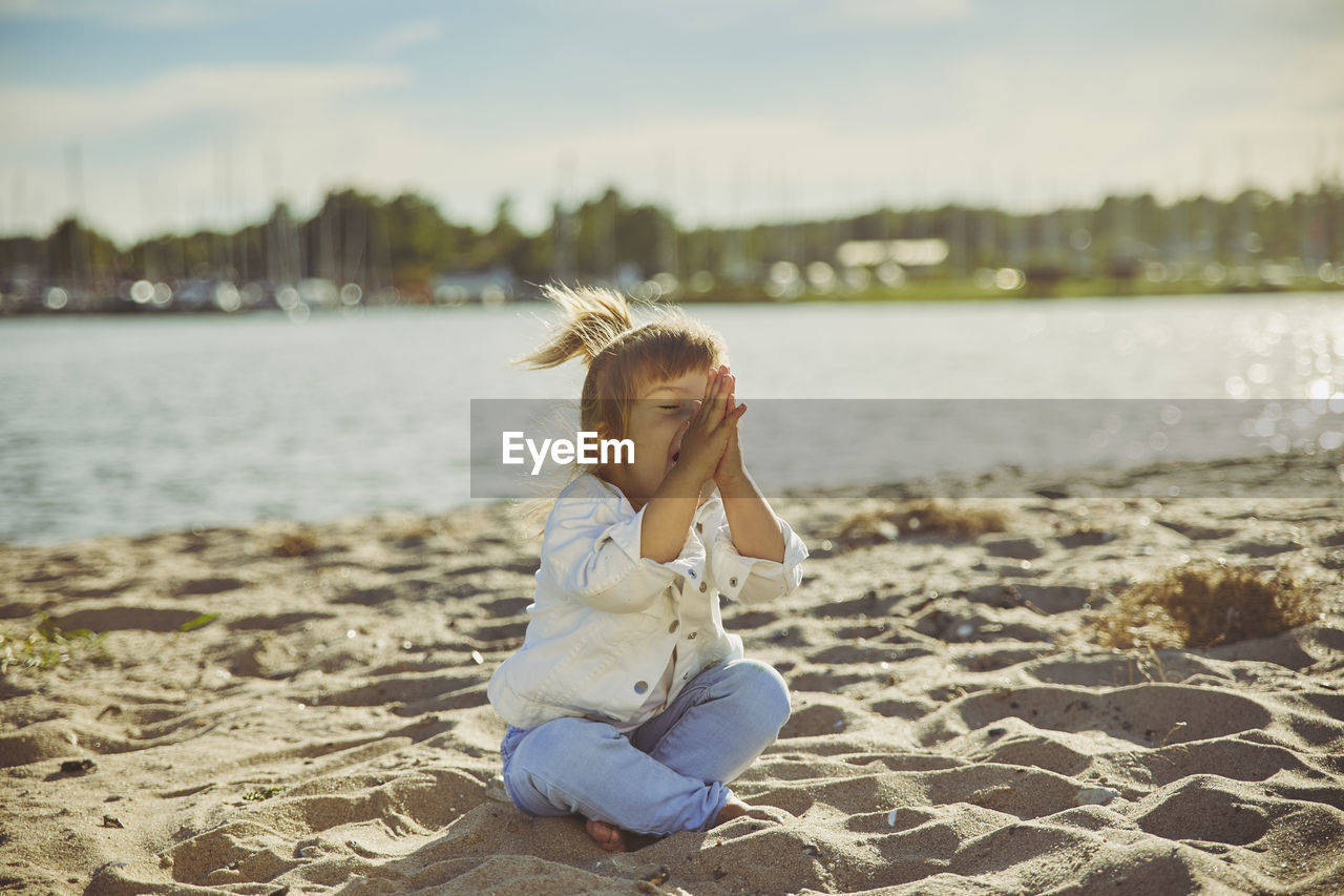 Charming child doing yoga on the beach