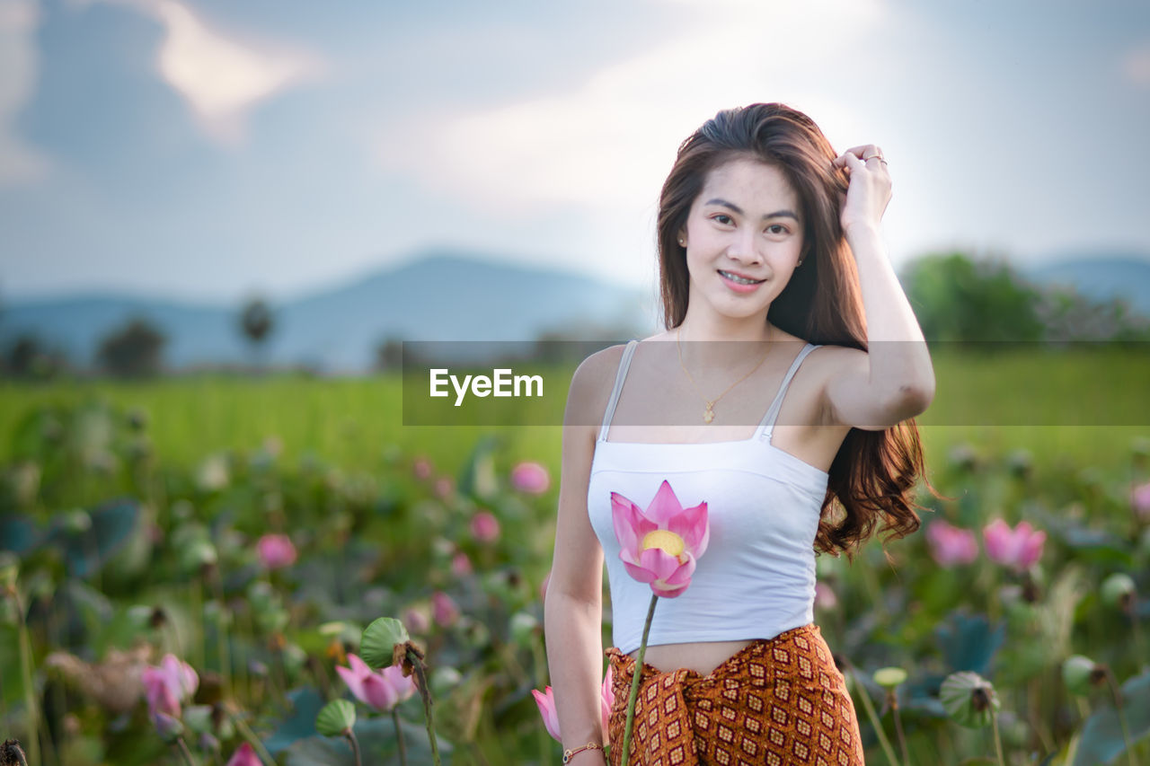 Portrait of smiling young woman standing on field