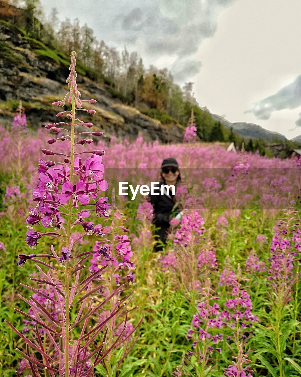 Woman standing amidst flowering plants against mountain