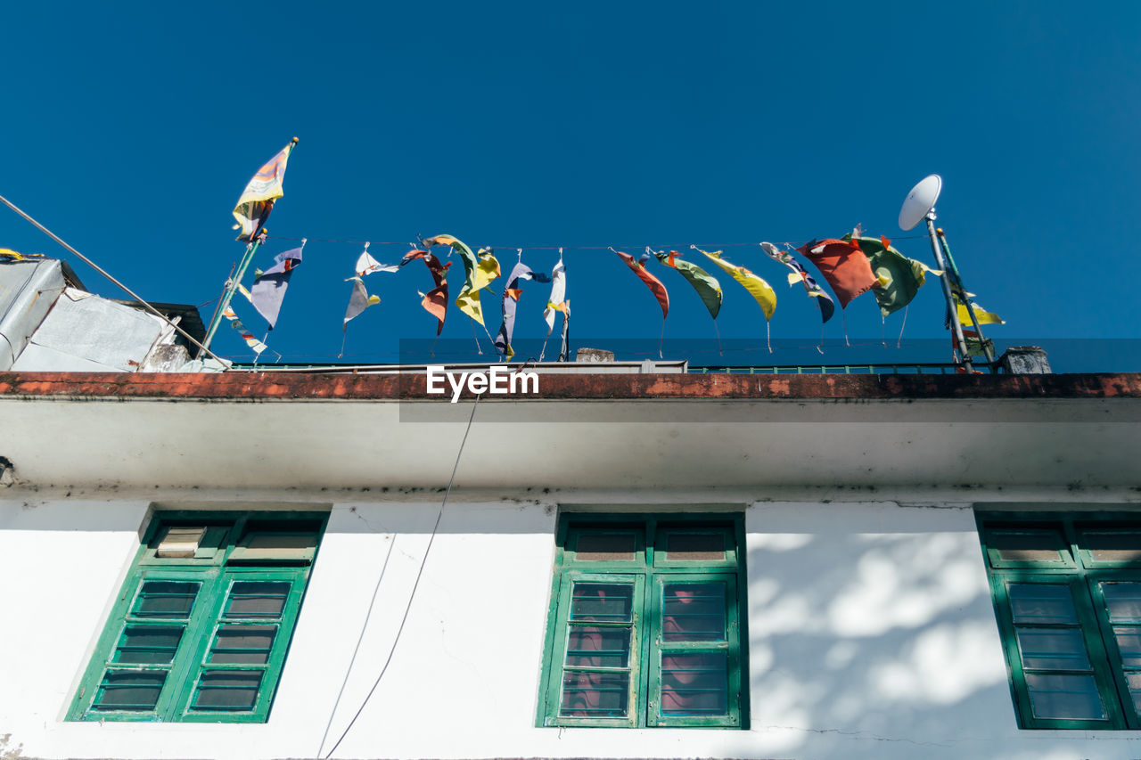 Low angle view of flags on building against blue sky