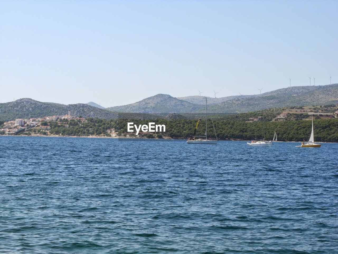 SCENIC VIEW OF CALM SEA AGAINST MOUNTAIN RANGE