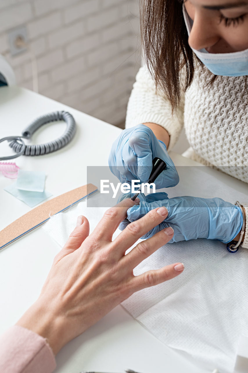 Young woman wearing glove and mask working at salon