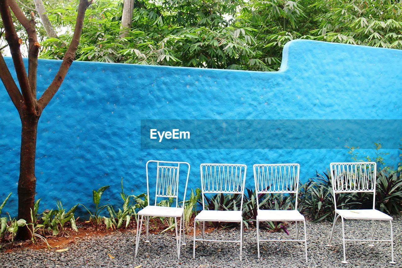 EMPTY CHAIRS AND TABLE BY SWIMMING POOL AGAINST SEA