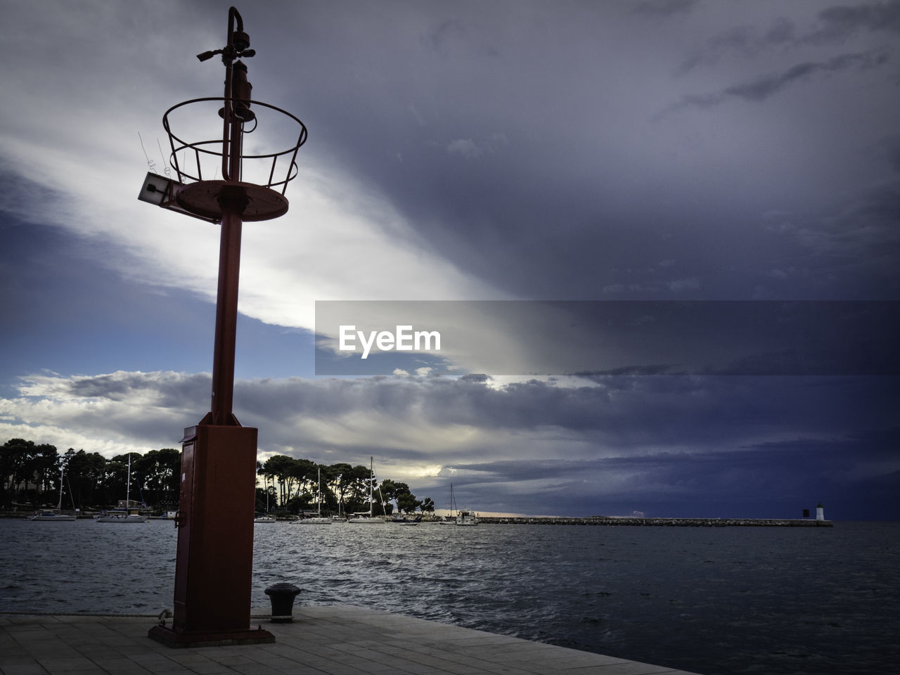 Street light by sea against sky at dusk