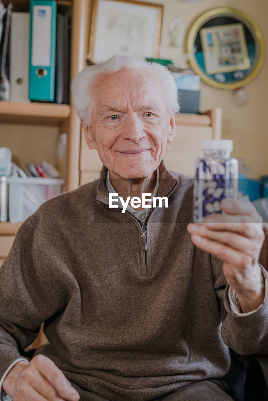 Smiling man holding medicines in bottle