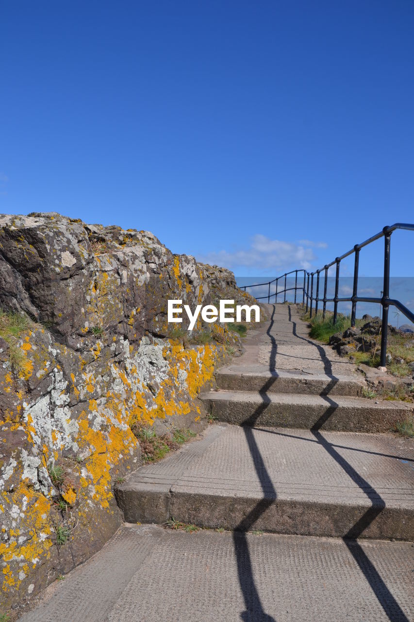 Surface level of road against clear blue sky