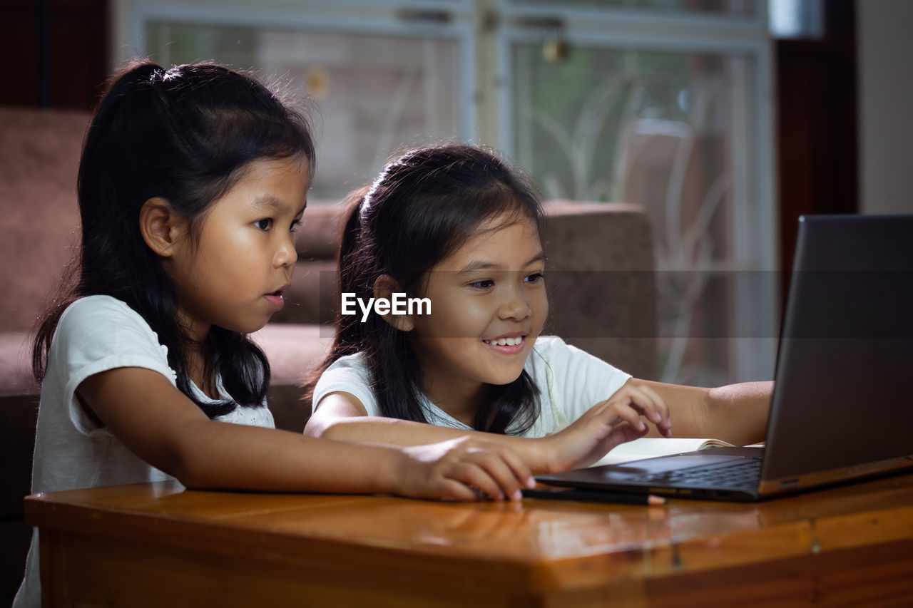 Siblings using laptop at desk