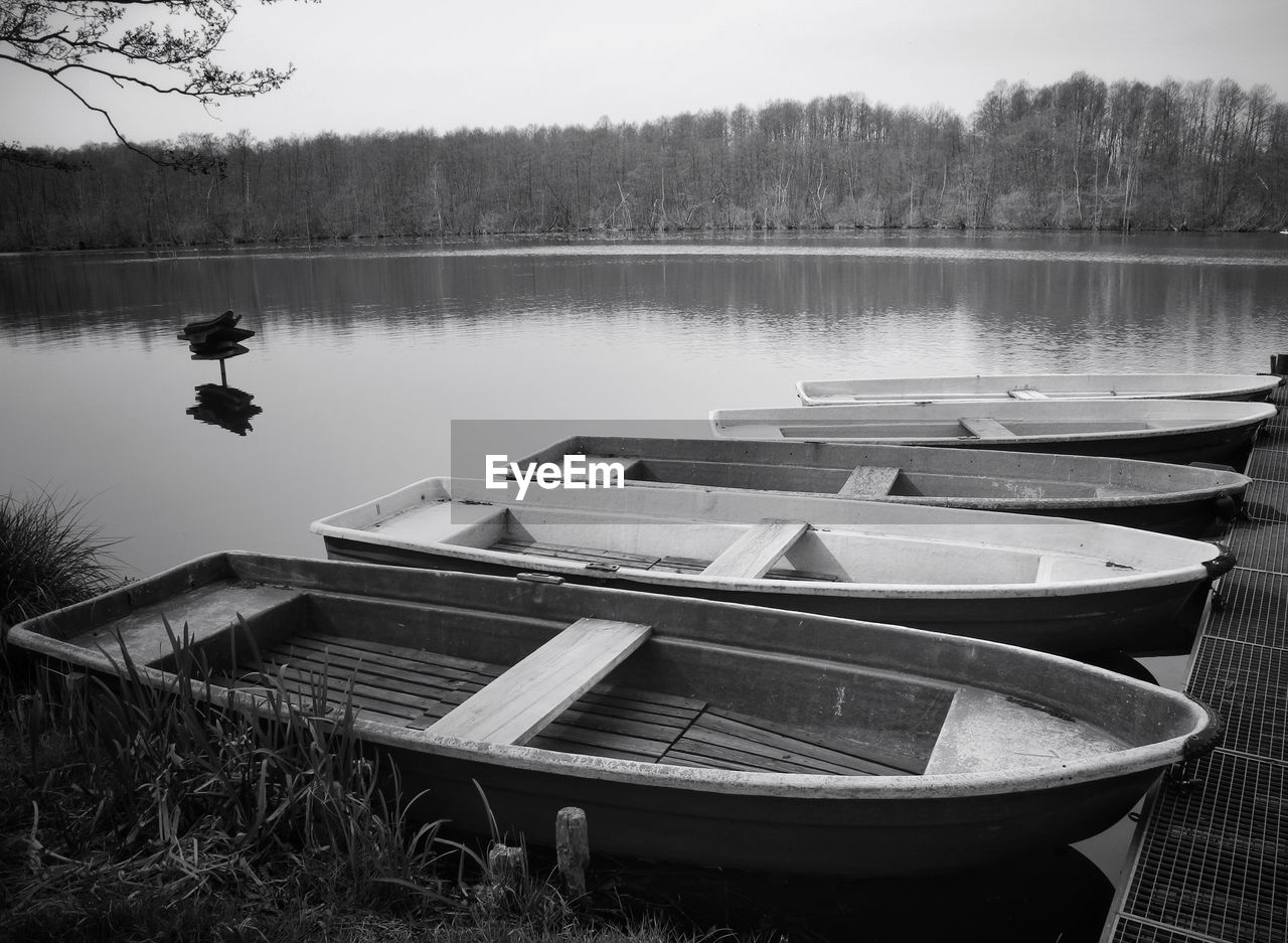 Side view of moored boats in calm lake