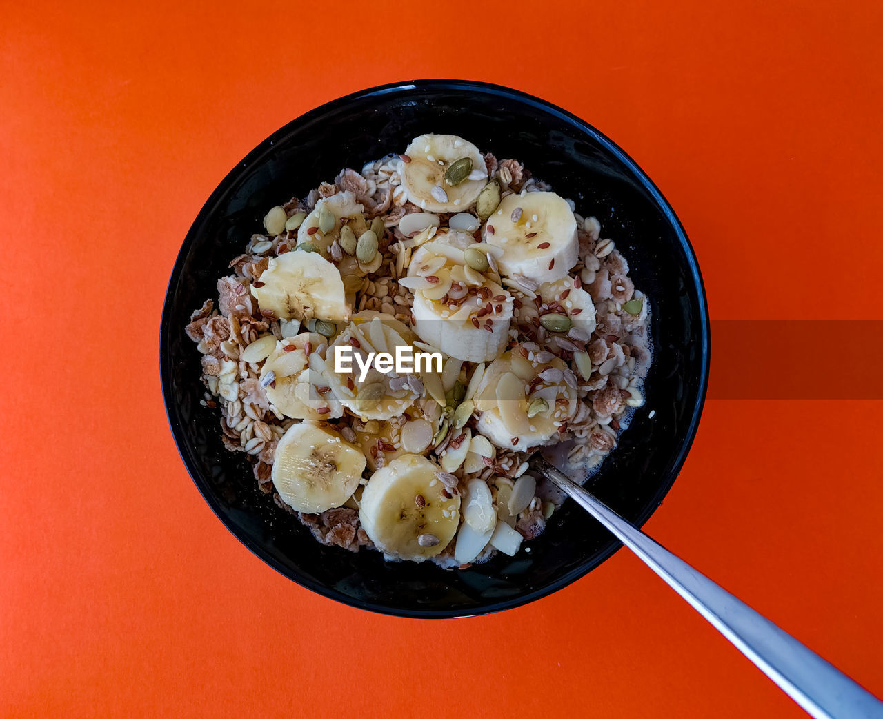 Black bowl of healthy oatmeal on orange backdrop