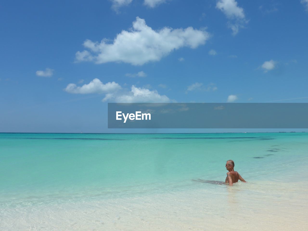 Senior man looking away while relaxing in sea