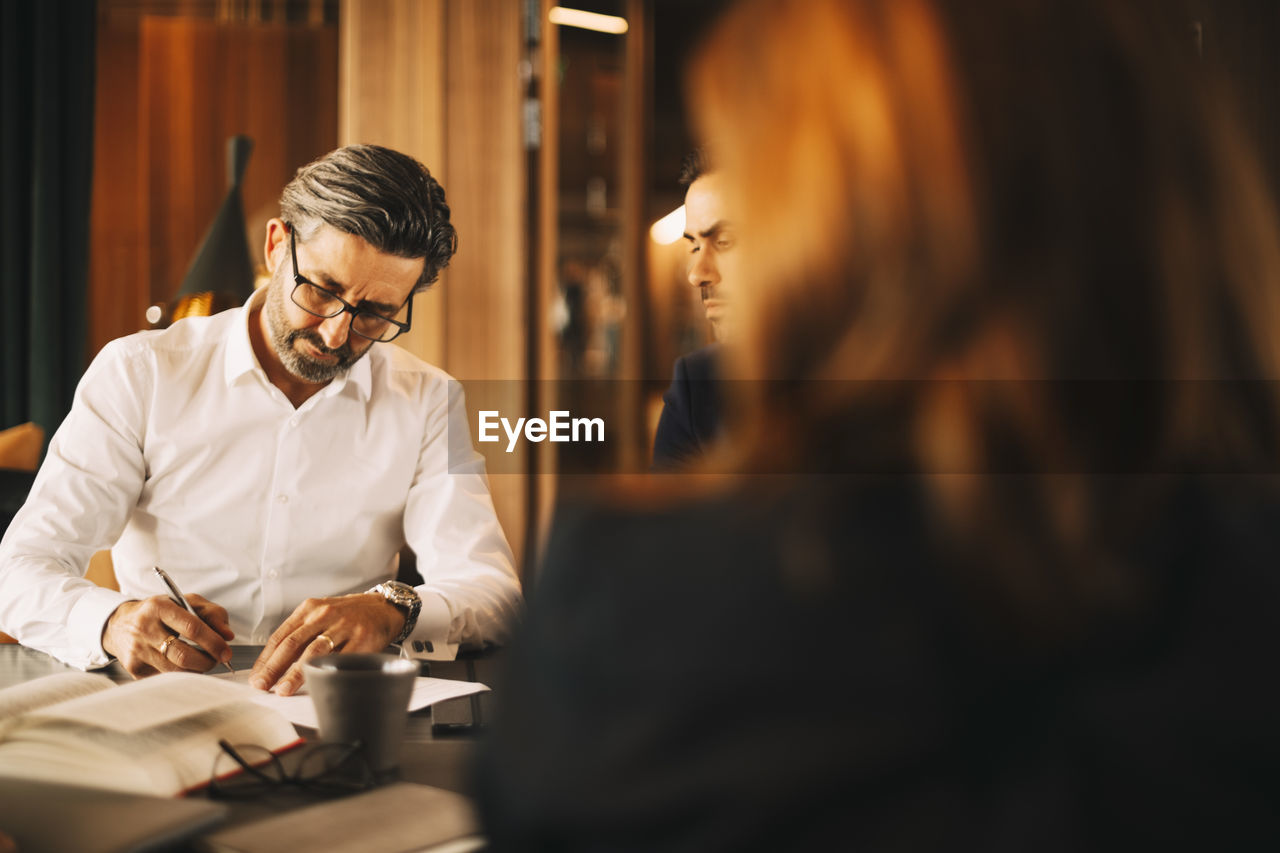 Mature lawyer signing documents during meeting at law office