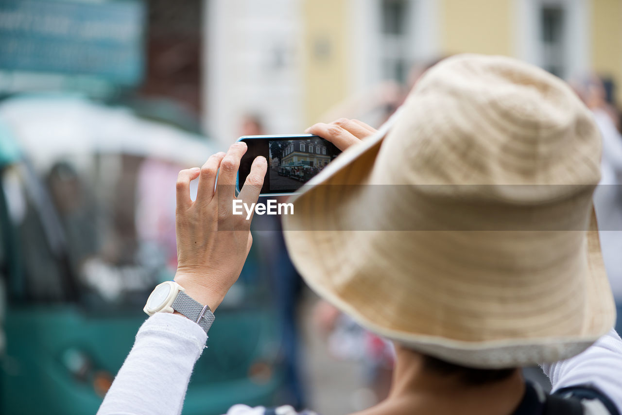 Rear view of woman wearing hat photographing with mobile phone