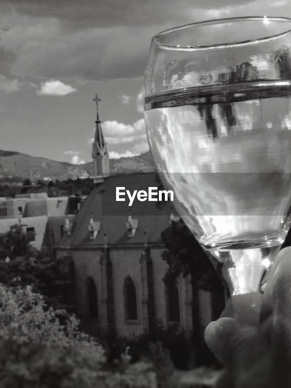 Cropped hand holding glass of drink against church
