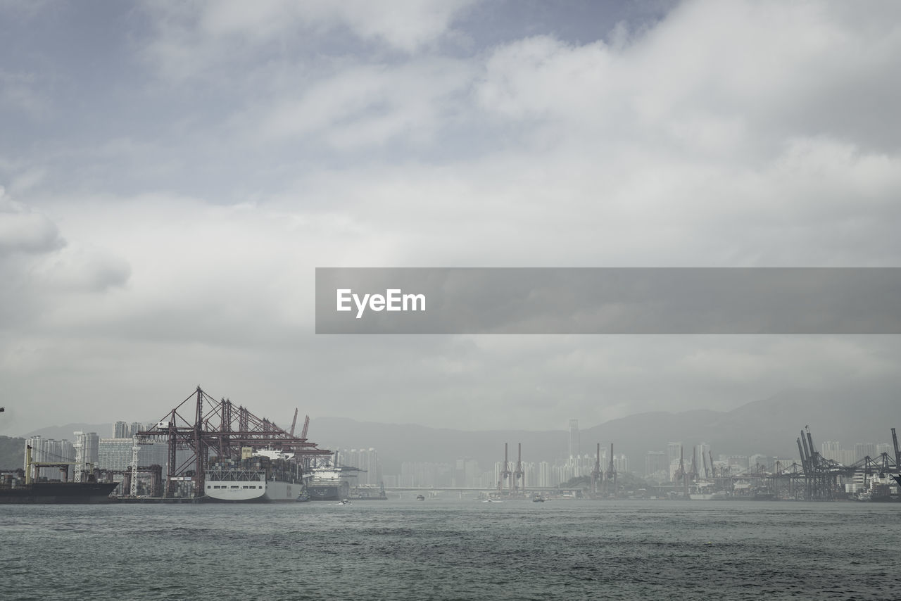 Commercial dock in sea against cloudy sky