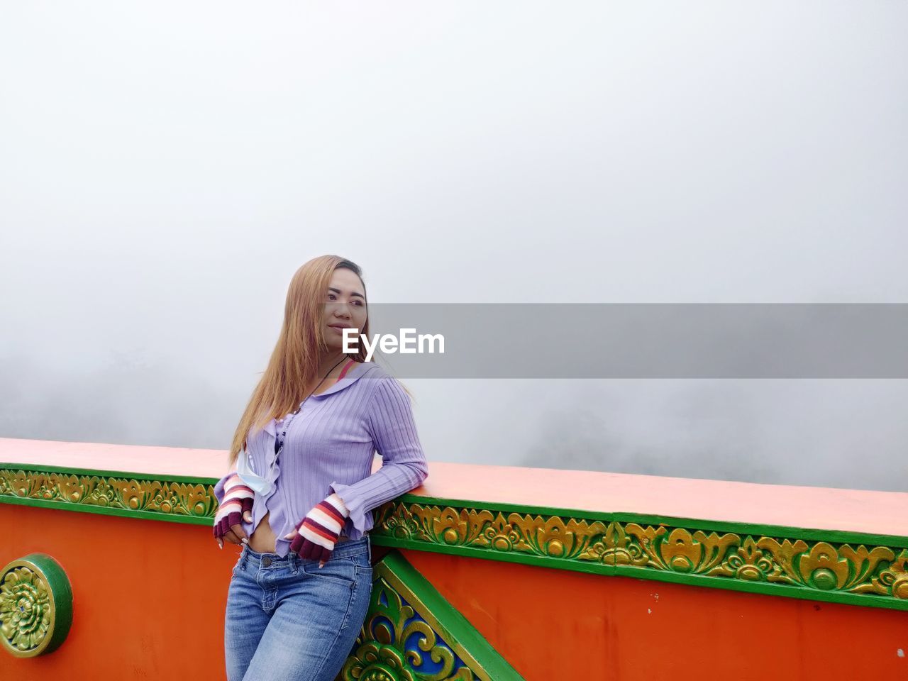 YOUNG WOMAN STANDING AGAINST SKY